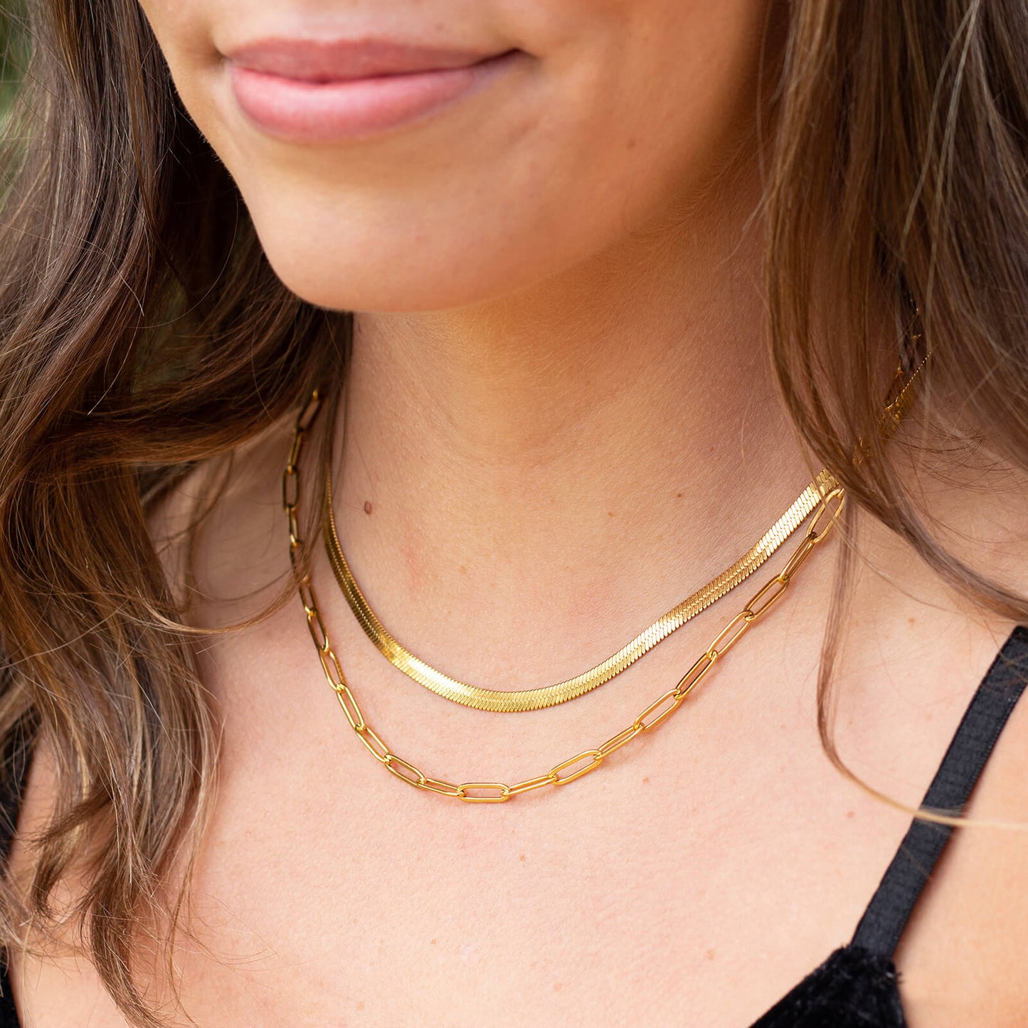 Woman wearing gold plated herringbone snake necklace and paperclip chain.