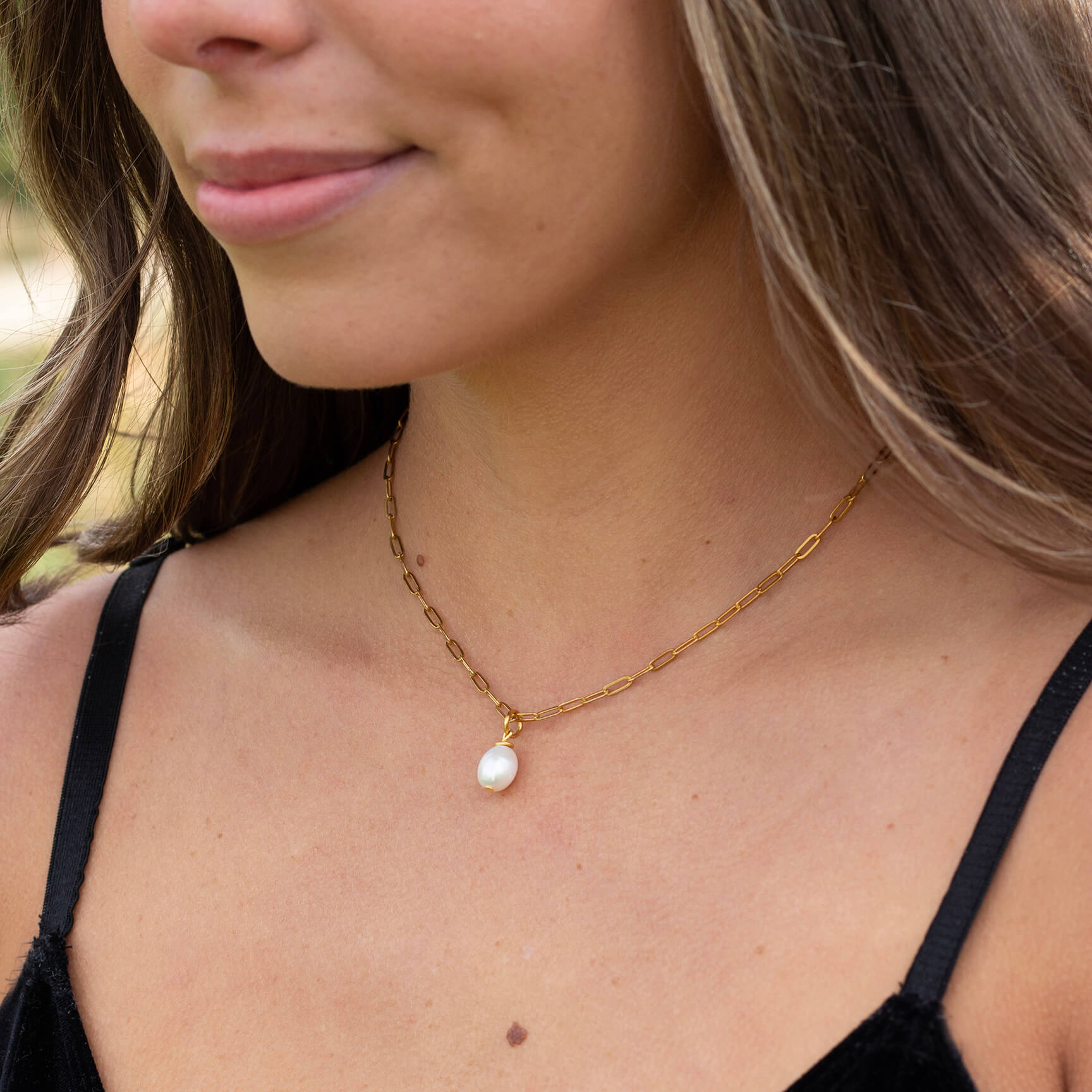 Woman wearing gold pearl paperclip necklace with waterproof chain.