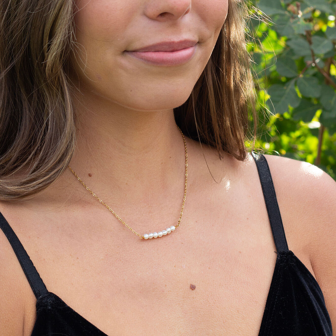 Woman wearing freshwater pearl bar necklace with gold chain