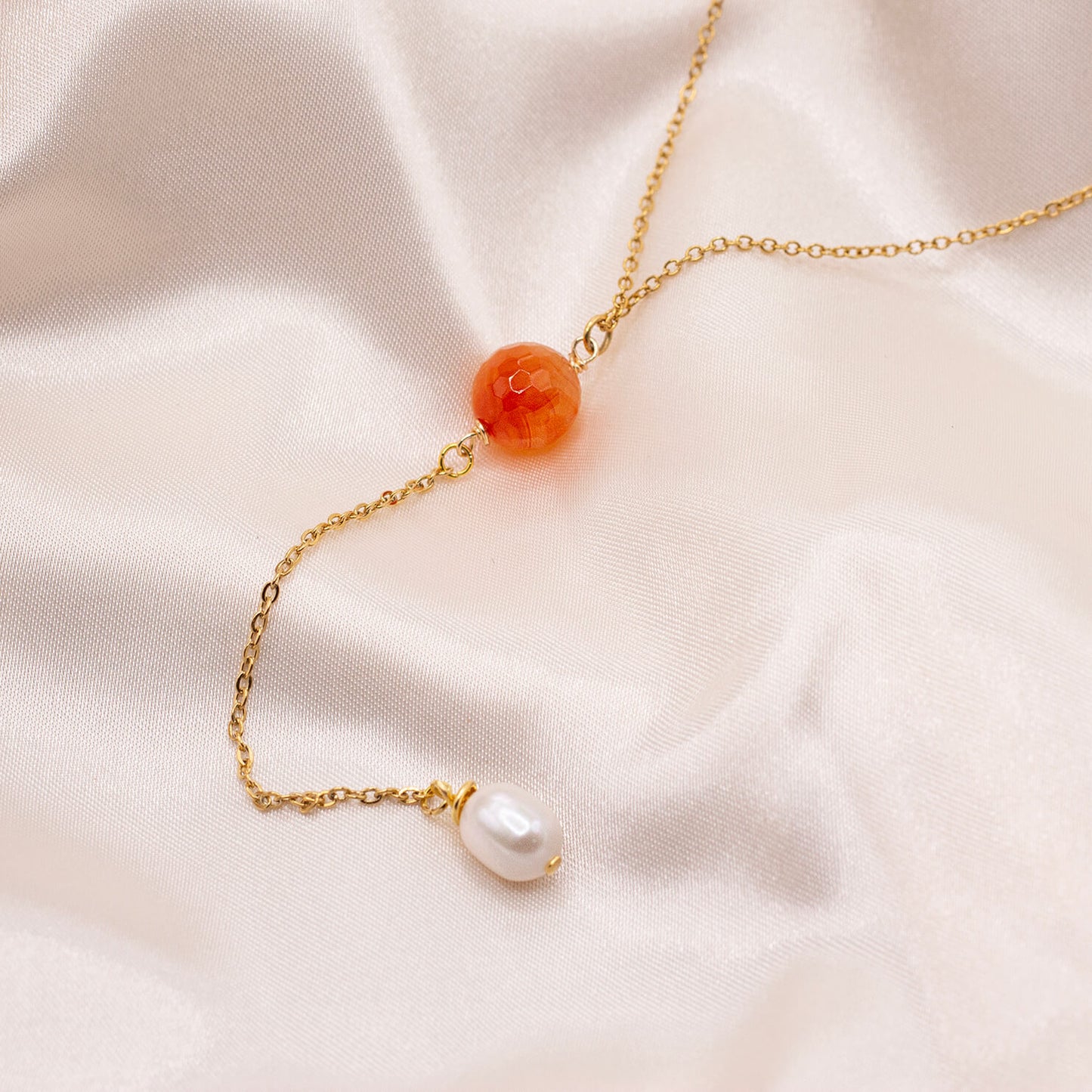 Orange red gemstone bead lariat necklace with dangling pearl. Hypoallergenic, gold-plated stainless steel. Water resistant.